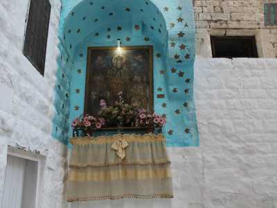 L'esempio di un'edicola ben curata nei pressi di strada San Marco. Spiccano il cielo stellato usato come sfondo e le composizioni floreali esposte poco sopra la tovaglia ricamata